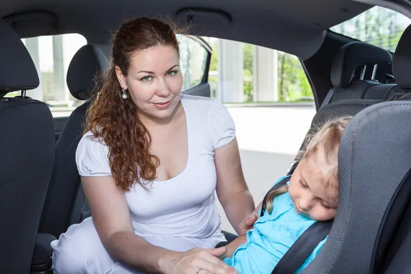 Mom wakes up sleeping daughter in a car safety seat — Stock Photo, Image