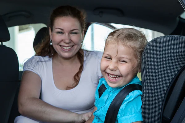 Laughing mother with small daughter in car safety seat — Stock Photo, Image