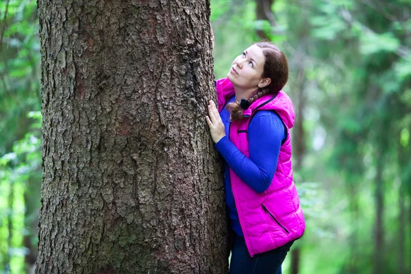 Женщина обнимает большое дерево в лесу — стоковое фото