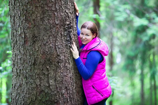 Kvinna kramas en stam i skogen — Stockfoto