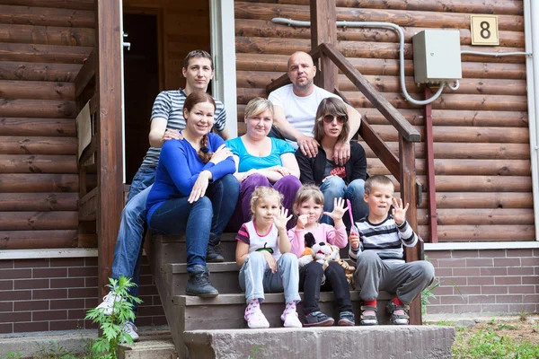 Stor kaukasiska familj sitter framför huset — Stockfoto