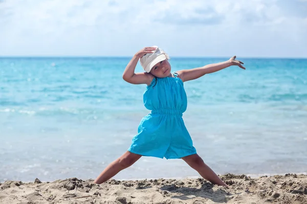 Liten flicka tränar yoga på stranden — Stockfoto