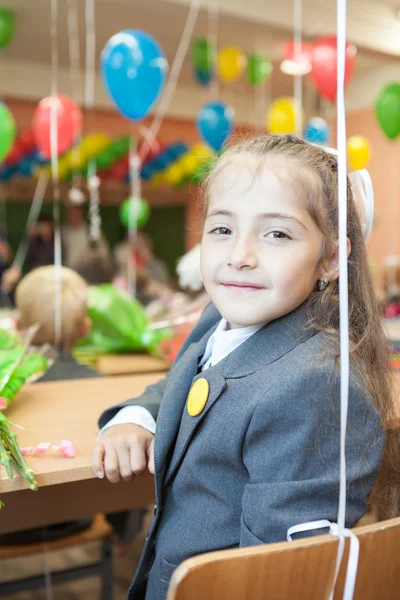 Weinig schoolmeisje zit aan Bureau in school — Stockfoto