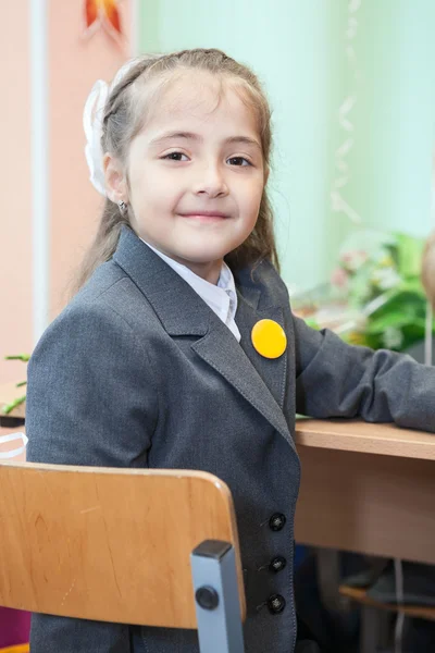 Weinig schoolmeisje zit aan Bureau in school — Stockfoto