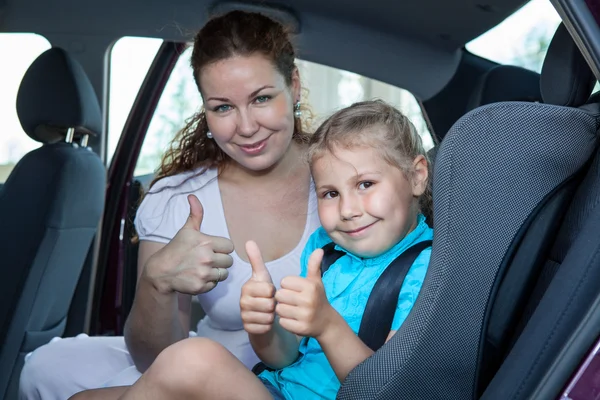 Madre e hijo mostrando un gesto de pulgar hacia arriba en el asiento de seguridad del automóvil Fotos de stock libres de derechos