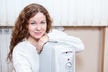 ısınmaya çalışırken radyatör yanında oturan kadın