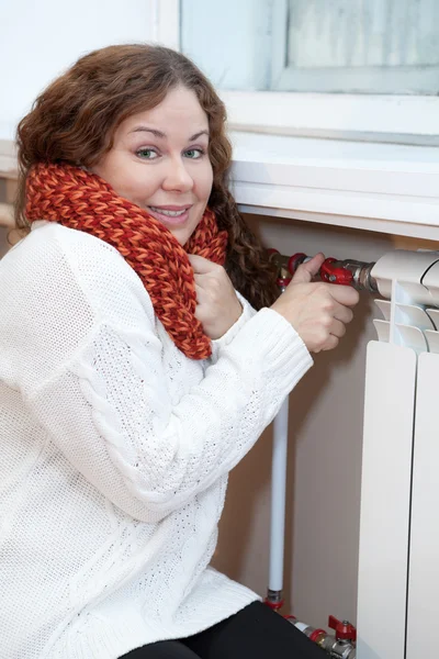 Lachende vrouw draaien thermostaat op centrale verwarming — Stockfoto