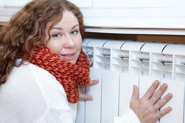 Young woman leaning to central heating convector — Stock Photo, Image