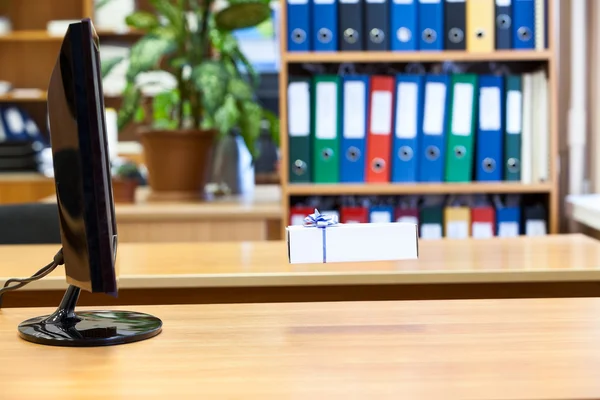 Geschenkbox hängt vor Monitor in der Luft — Stockfoto