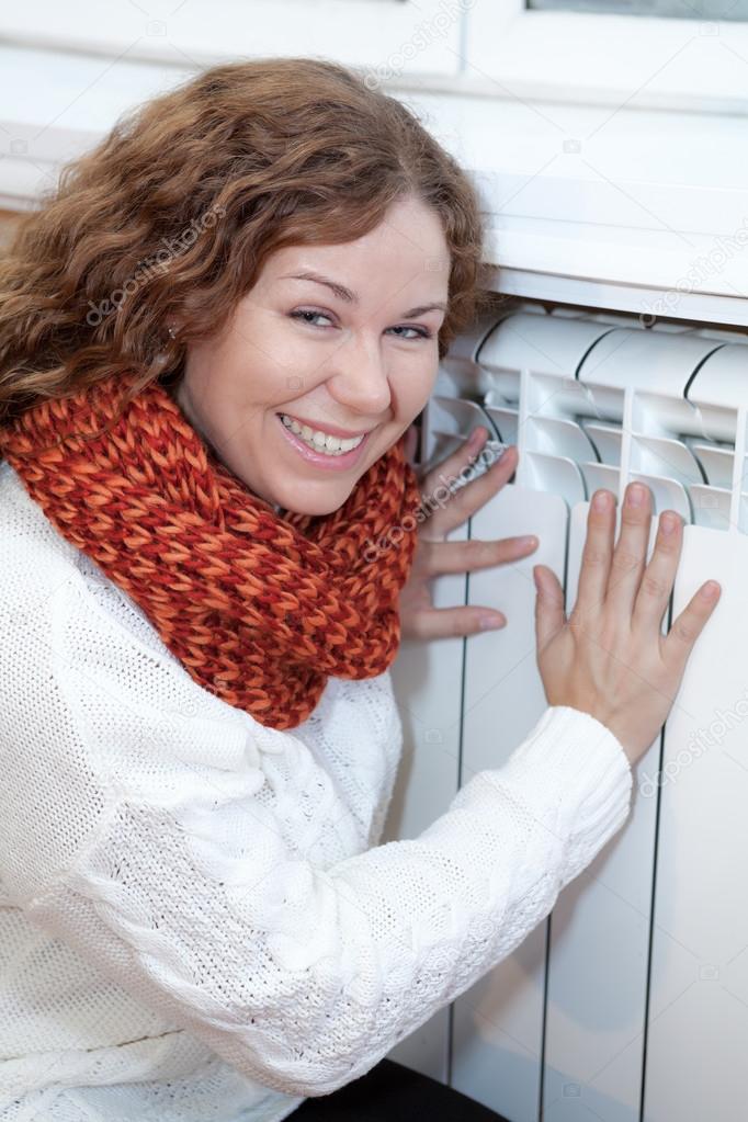 Woman touching warm central heating convector