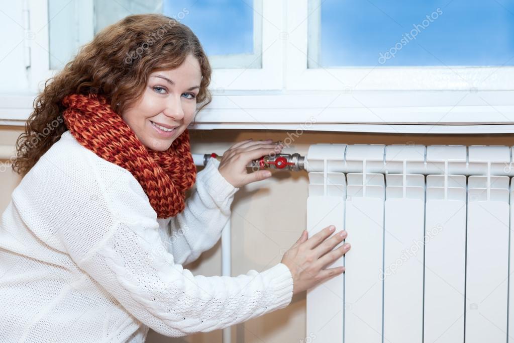 Woman in front of heating radiator in domestic room