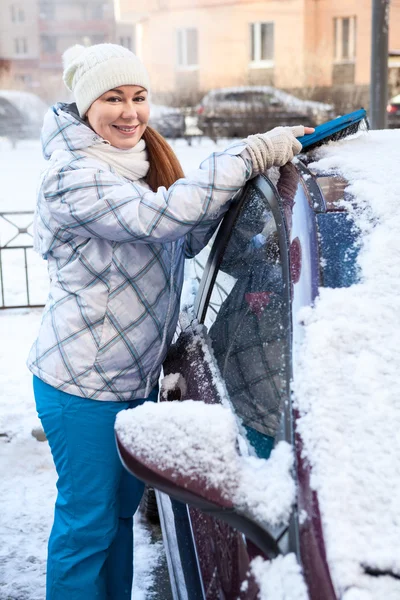 Mulher feliz, remoção da neve da capota do carro no inverno — Fotografia de Stock