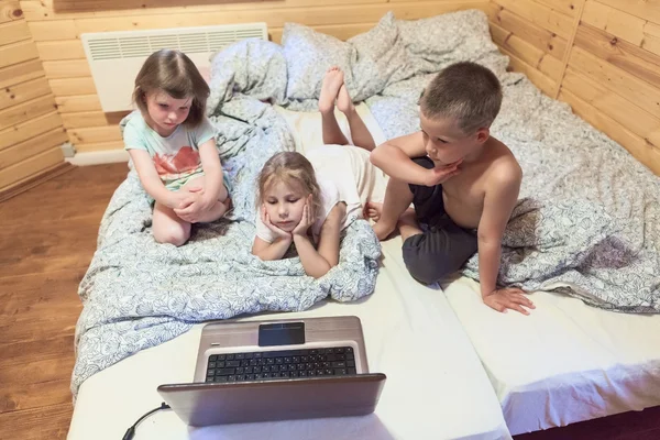 Tre barn tittar på laptop — Stockfoto