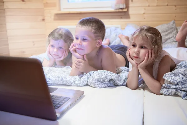 Tres niños mirando el portátil — Foto de Stock