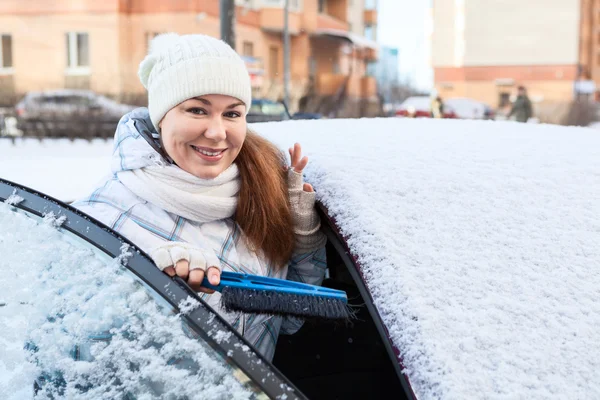 Mujer con cepillo de nieve cerca de coche cubierto de nieve —  Fotos de Stock