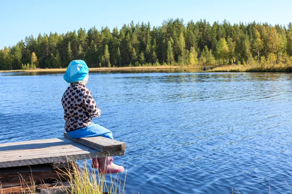 Child sitting on wooden jetty — Stock Photo, Image