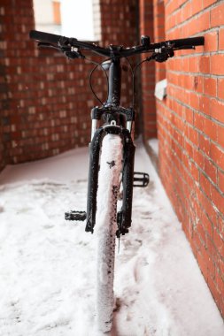 Bisikletin önü karlı balkonda duruyor, soğuk kış mevsiminde ata biniyor.