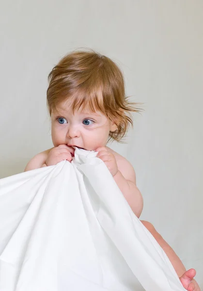 Schattige babymeisje bijt witte doek rand — Stockfoto