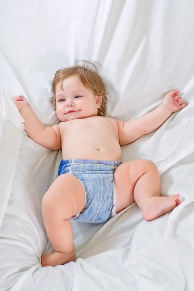 Bonito bebê menina sorri no pano branco — Fotografia de Stock
