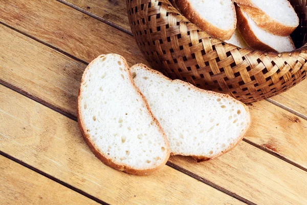Two slices of bread near wicker breadbasket — Stock Photo, Image