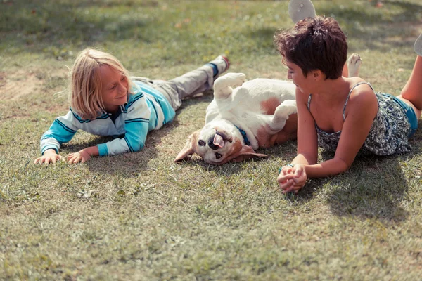 Двоє дітей грають з собакою — стокове фото