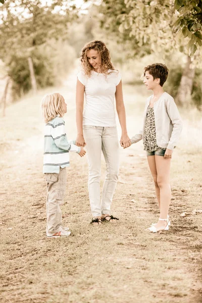 Schöne junge Frau mit zwei Kindern draußen — Stockfoto