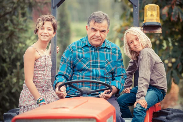 Взрослый фермер с детьми на тракторе — стоковое фото