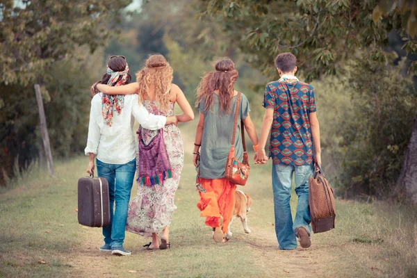 Grupo Hippie Caminhando em uma estrada do campo — Fotografia de Stock
