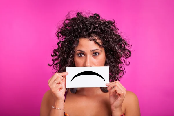 Mujer joven con emoticono triste sobre fondo fucsia —  Fotos de Stock