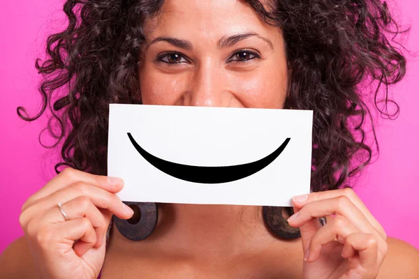 Junge Frau mit Smiley-Emoticon auf Fuchsia-Hintergrund — Stockfoto