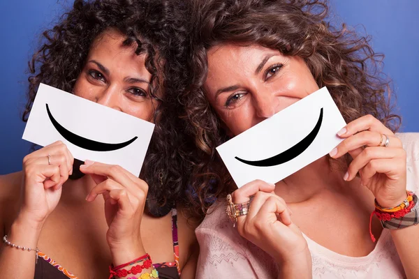 Twee jonge vrouwen met smiley emoticon op blauwe achtergrond — Stockfoto