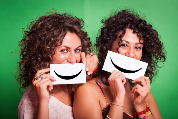 Duas mulheres jovens com Smiley Emoticon em fundo verde — Fotografia de Stock