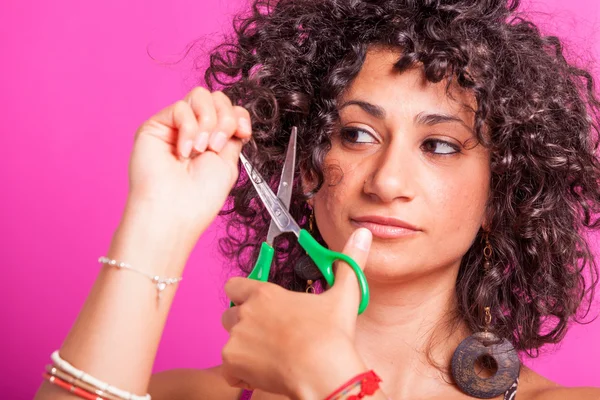 Jovem mulher cortando seus cabelos encaracolados — Fotografia de Stock