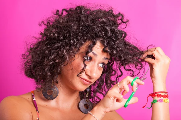 Giovane donna tagliando i suoi capelli ricci — Foto Stock