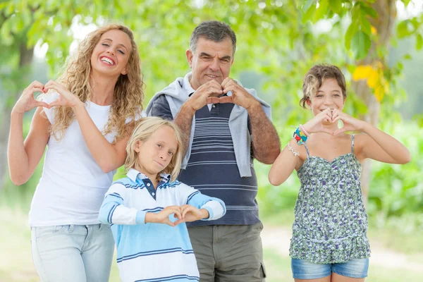 Ευτυχισμένη οικογένεια με τα χέρια σε σχήμα καρδιάς — Φωτογραφία Αρχείου