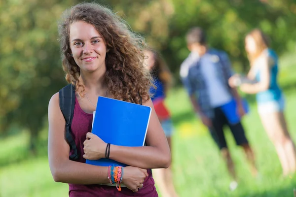 Mladá studentka v parku s dalšími přáteli — Stock fotografie