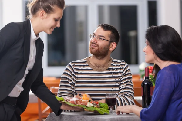 Jong koppel in restaurant met serveerster — Stockfoto