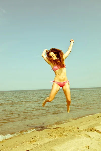 Glückliche Frau springt am Strand am Meer — Stockfoto