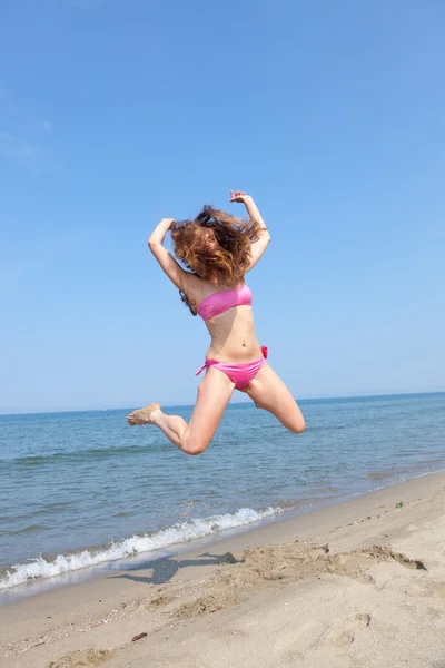 Ευτυχισμένη γυναίκα άλμα στην παραλία στο παραθαλάσσιο — Φωτογραφία Αρχείου