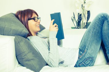 Kanepenin üzerine bir kitap ile güzel bir genç kadın