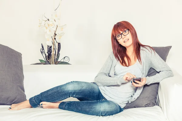 Mulher bonita com Smartphone no sofá — Fotografia de Stock