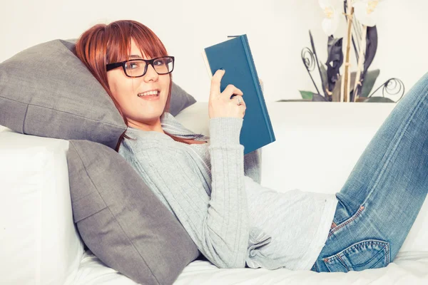 Hermosa joven con un libro en el sofá —  Fotos de Stock