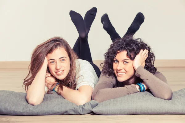 Twee mooie vrouwen liggen met kussen — Stockfoto