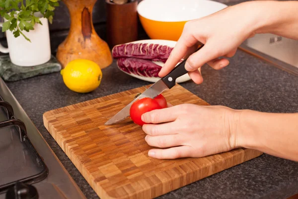 Femme coupant la tomate dans la cuisine — Photo