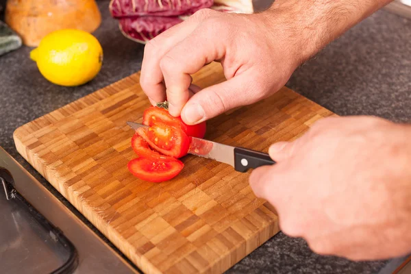 Man snijden tomaat in de keuken — Stockfoto
