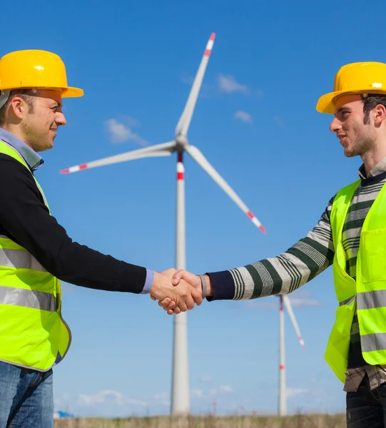 Инженеры, пожимающие руку на ветряной электростанции — стоковое фото