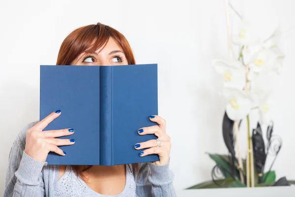 Schöne junge Frau mit einem Buch auf dem Sofa — Stockfoto