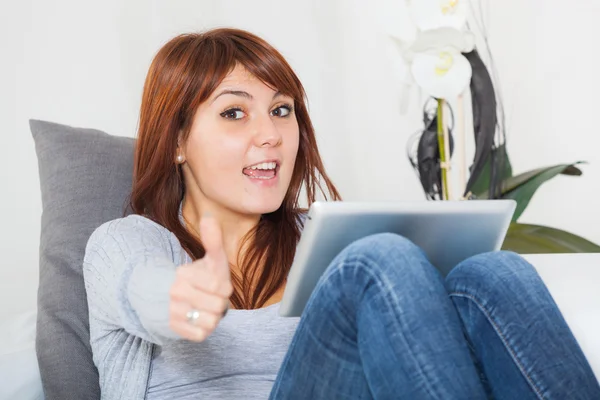 Schöne junge Frau mit Tablet-PC auf dem Sofa — Stockfoto