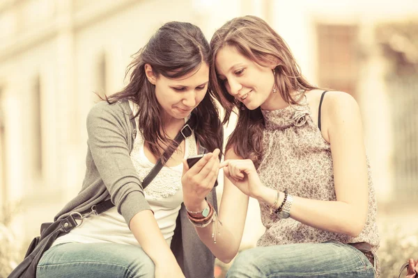 Duas mulheres bonitas enviando mensagens com celular — Fotografia de Stock