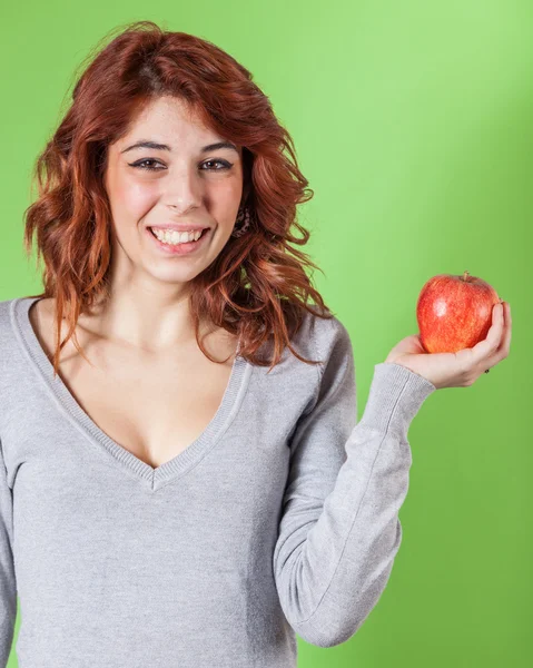 緑の背景に赤いリンゴを保持している 10 代の少女 — ストック写真